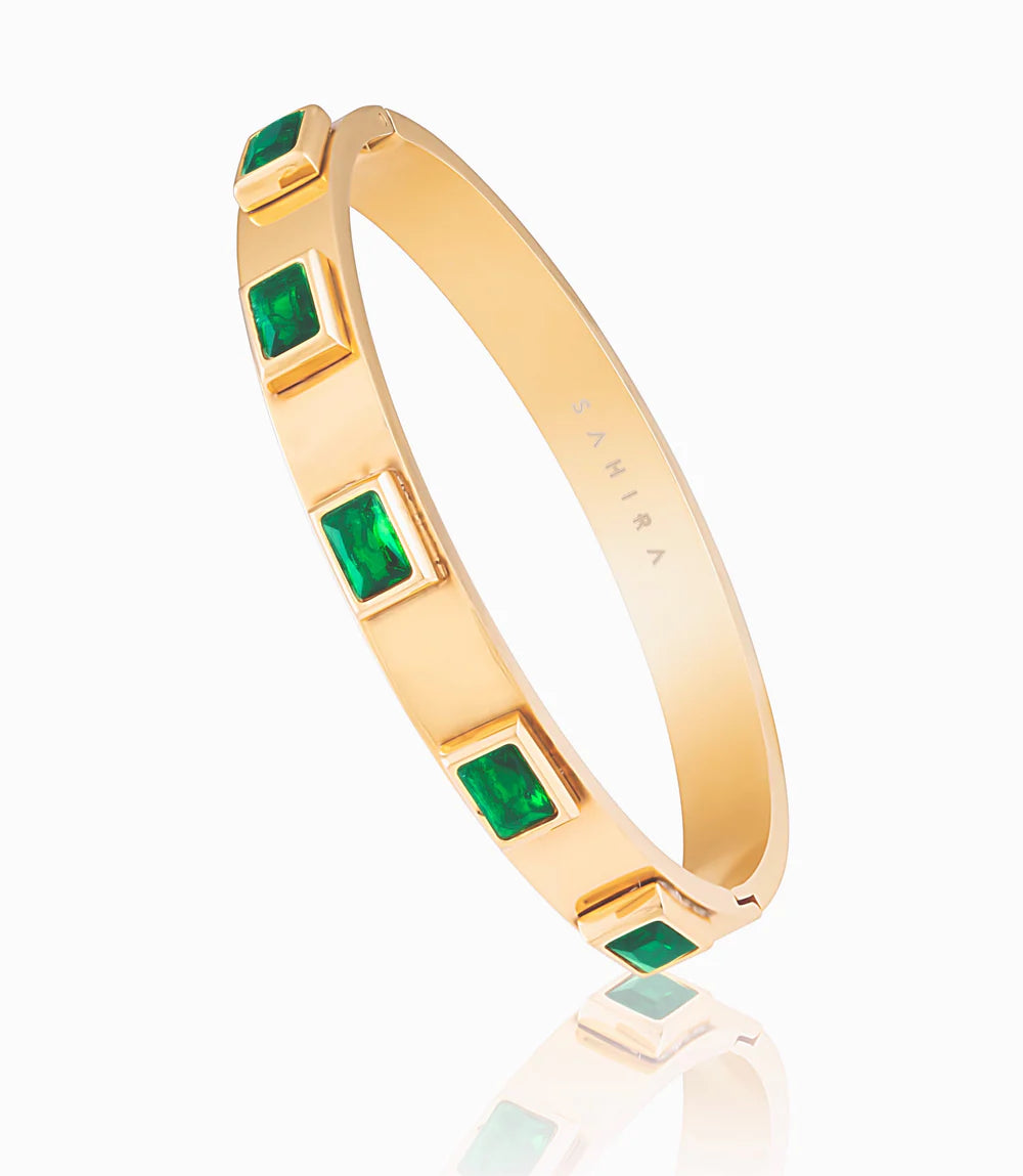 Gold bangle bracelet with emerald accent stones.